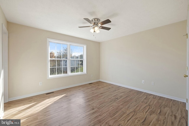 spare room featuring a textured ceiling, wood-type flooring, and ceiling fan