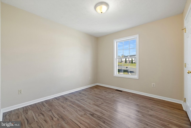 unfurnished room featuring hardwood / wood-style floors and a textured ceiling