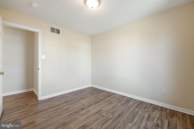 spare room featuring dark wood-type flooring and a textured ceiling