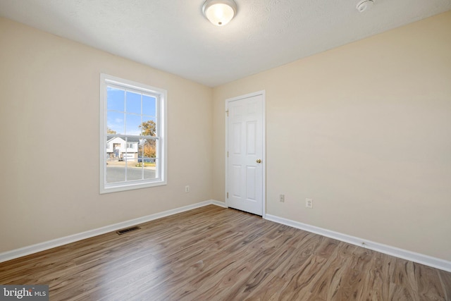 unfurnished room with light wood-type flooring and a textured ceiling