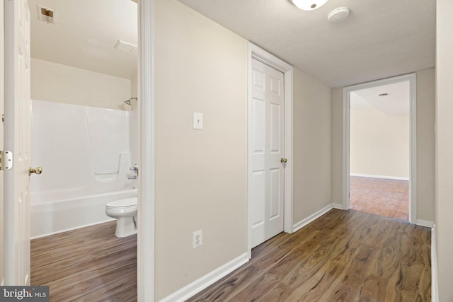 corridor with dark hardwood / wood-style flooring and a textured ceiling