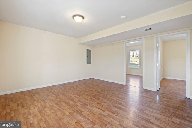 empty room with electric panel and light hardwood / wood-style floors