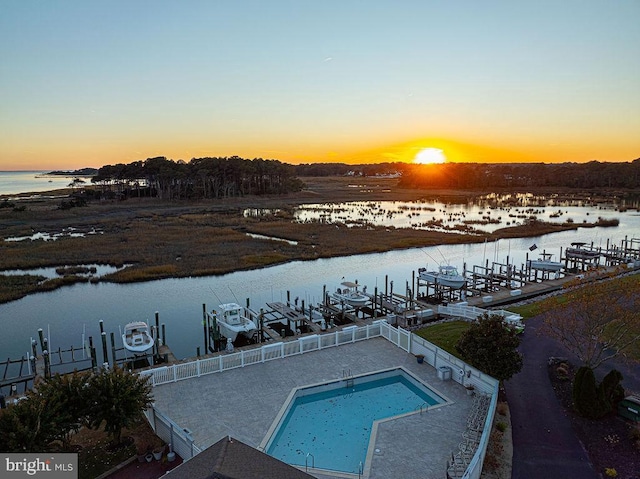 pool at dusk featuring a water view