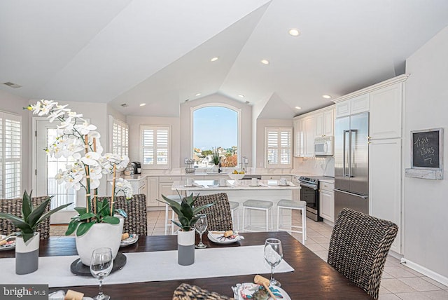 tiled dining room featuring vaulted ceiling