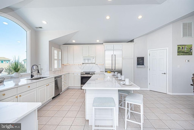 kitchen featuring stainless steel appliances, backsplash, sink, a breakfast bar, and white cabinets