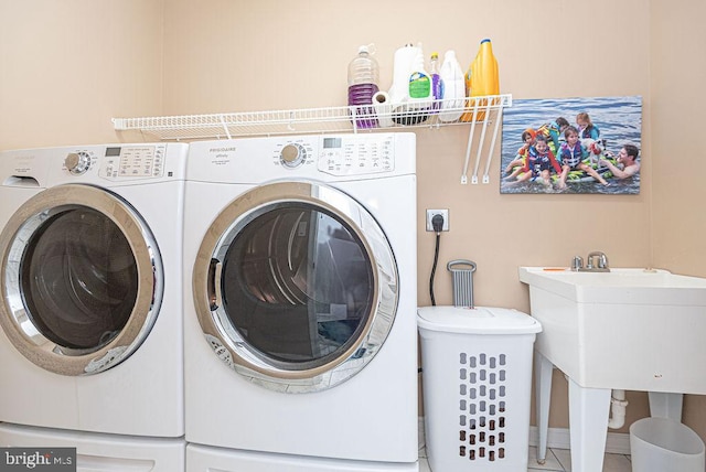 laundry area featuring sink, tile patterned floors, and washing machine and clothes dryer