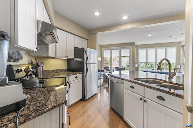 kitchen featuring wall chimney exhaust hood, white cabinets, stainless steel appliances, and sink