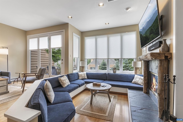 living room with a healthy amount of sunlight, light hardwood / wood-style flooring, and a high end fireplace