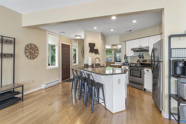 kitchen featuring a baseboard radiator, light wood-type flooring, stainless steel appliances, and a healthy amount of sunlight