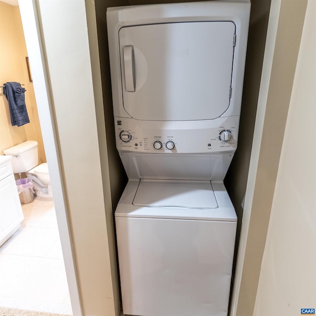 laundry area featuring light tile patterned floors and stacked washer and dryer