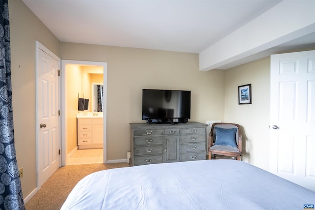 bedroom featuring ensuite bathroom and light colored carpet