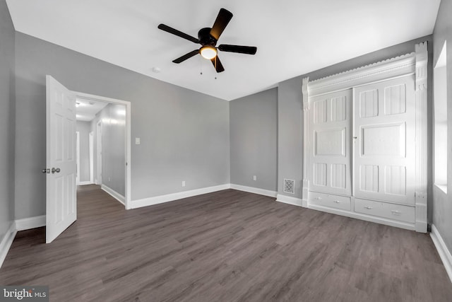 unfurnished bedroom featuring ceiling fan, a closet, and dark hardwood / wood-style flooring