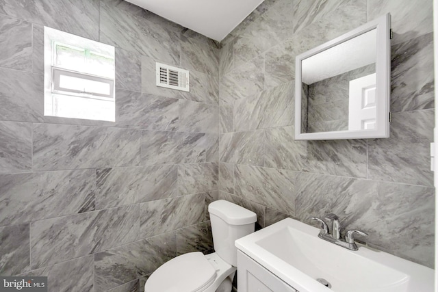 bathroom featuring vanity, toilet, and tile walls