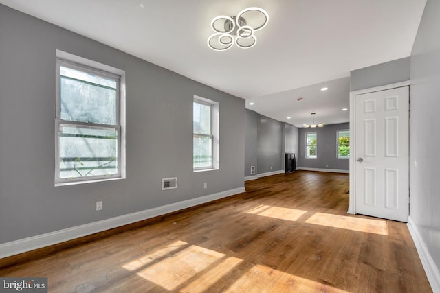 unfurnished room featuring an inviting chandelier and light wood-type flooring