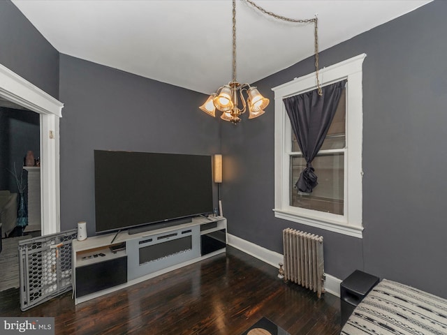 living room featuring dark hardwood / wood-style flooring, an inviting chandelier, and radiator