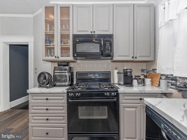 kitchen with dark wood-type flooring, backsplash, ornamental molding, black appliances, and light stone counters