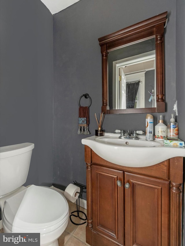 bathroom with toilet, vanity, and tile patterned floors