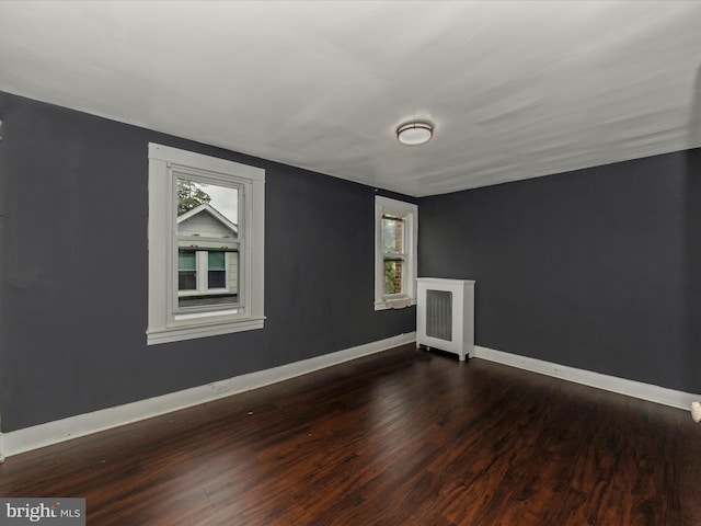 spare room with radiator, dark wood-type flooring, and a wealth of natural light