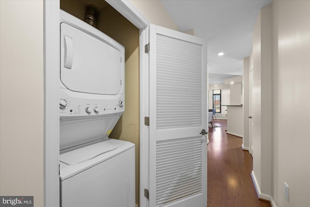 laundry area with stacked washer / dryer and dark wood-type flooring