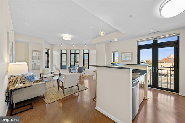 kitchen featuring french doors, dark hardwood / wood-style floors, stainless steel dishwasher, and hanging light fixtures