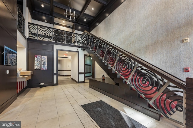 stairway featuring beamed ceiling, tile patterned floors, a high ceiling, and coffered ceiling