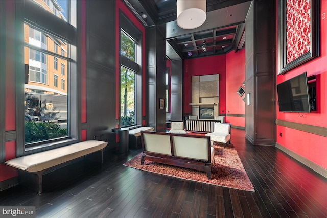 interior space featuring hardwood / wood-style floors, coffered ceiling, a high ceiling, and a tiled fireplace