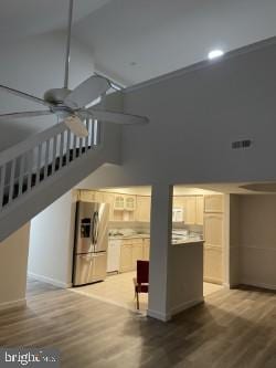 unfurnished living room featuring ceiling fan, light wood-type flooring, and high vaulted ceiling