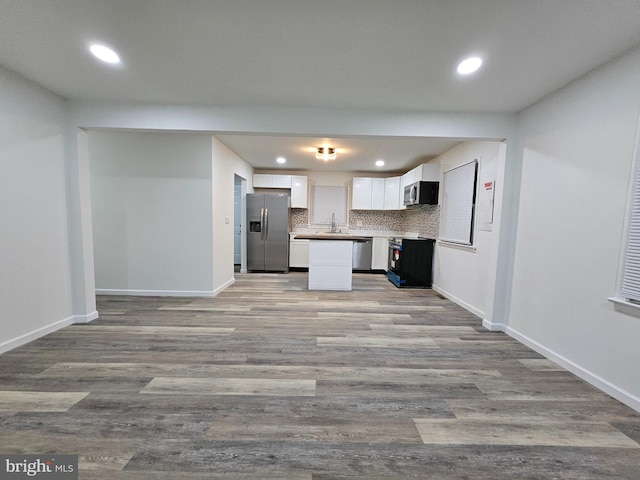 kitchen featuring stainless steel appliances, a center island, sink, white cabinetry, and light wood-type flooring