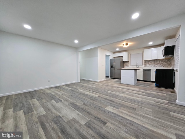 kitchen featuring backsplash, appliances with stainless steel finishes, sink, white cabinets, and light hardwood / wood-style flooring