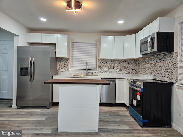 kitchen featuring stainless steel appliances, white cabinetry, decorative backsplash, sink, and light hardwood / wood-style floors