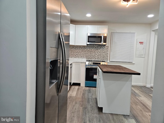 kitchen featuring stainless steel appliances, hardwood / wood-style flooring, wooden counters, backsplash, and white cabinets