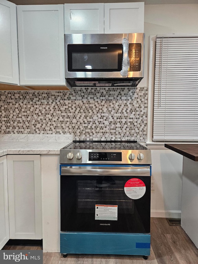 kitchen featuring white cabinetry, appliances with stainless steel finishes, dark hardwood / wood-style floors, and tasteful backsplash