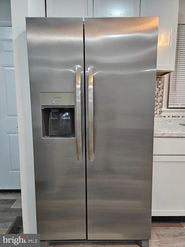 details featuring white cabinets, light stone counters, stainless steel fridge, and dark hardwood / wood-style floors