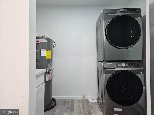 laundry area with electric water heater, stacked washer and clothes dryer, and wood-type flooring