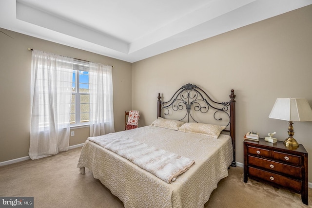 bedroom featuring light colored carpet and a tray ceiling