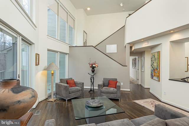 living room with dark hardwood / wood-style flooring, plenty of natural light, and a towering ceiling