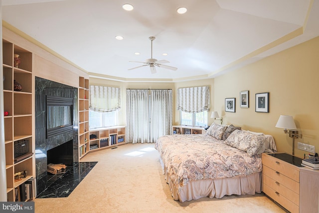 bedroom featuring multiple windows, ceiling fan, a fireplace, and light colored carpet