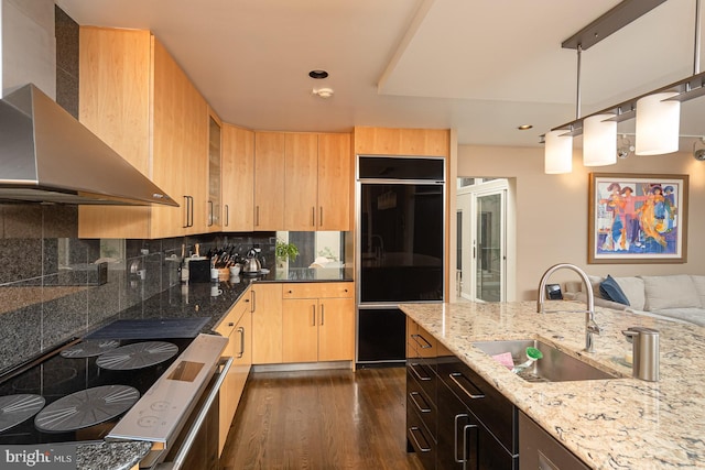 kitchen with light brown cabinets, sink, wall chimney exhaust hood, light stone countertops, and dark hardwood / wood-style flooring