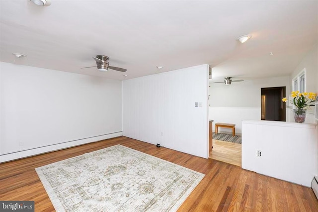 empty room with wood-type flooring, a baseboard radiator, and ceiling fan