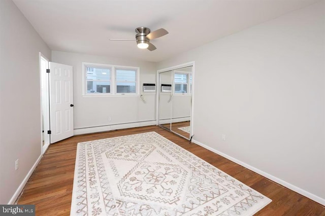 interior space with baseboard heating, wood-type flooring, and ceiling fan