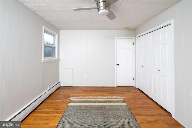 unfurnished bedroom featuring ceiling fan, hardwood / wood-style flooring, and a baseboard radiator