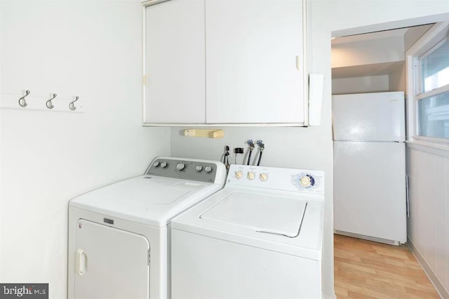 laundry area with light hardwood / wood-style floors, cabinets, and independent washer and dryer