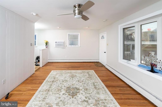 laundry room featuring light hardwood / wood-style flooring, a baseboard heating unit, and ceiling fan