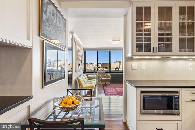 kitchen featuring dark hardwood / wood-style flooring, stainless steel microwave, and white cabinetry