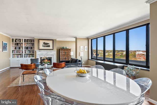 dining area with a high end fireplace, hardwood / wood-style floors, built in features, and crown molding