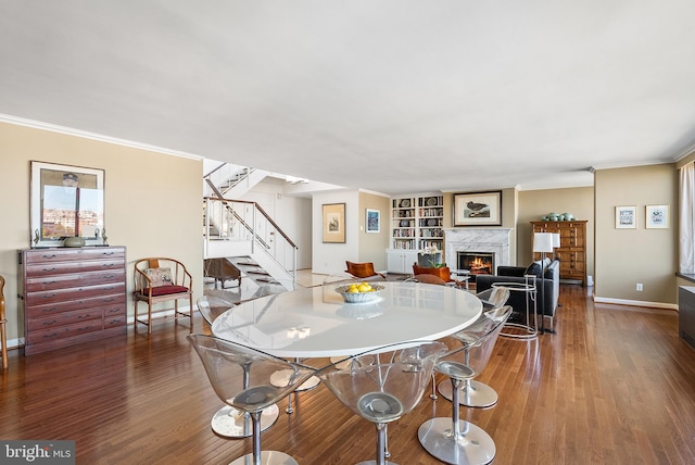 dining area with a high end fireplace, hardwood / wood-style flooring, and crown molding