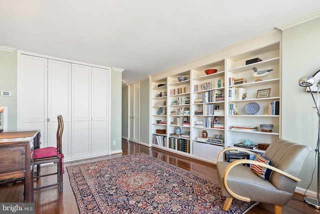 sitting room with dark wood-type flooring and ornamental molding