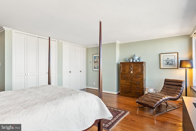 bedroom with hardwood / wood-style floors, crown molding, and multiple closets