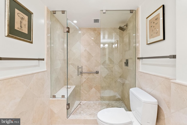 bathroom with a shower with door, tile walls, and toilet