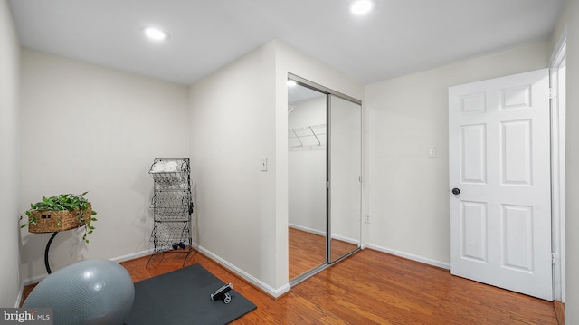 exercise area with wood finished floors, recessed lighting, and baseboards